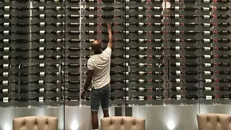 Floyd Mayweather reaching for a bottle of wine from his wine cellar in his home
