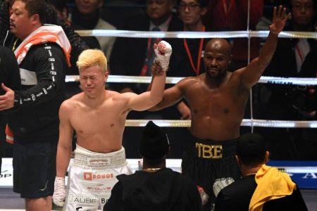 Floyd Mayweather holding Tenshin's hand in the air as he signals for victory, but Tenshin is grunting with his other hand down. The fight increased Floyd's net worth by $9 million.