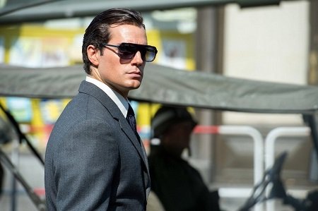 Henry Cavill wearing suit and glasses like James Bond.