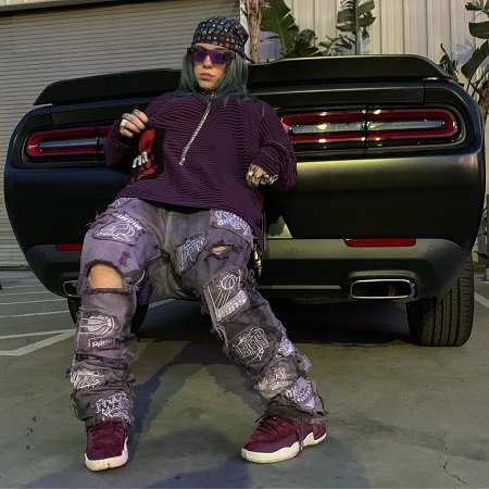 Billie Eilish trying to hide the license plate of her Dodge Challenger.