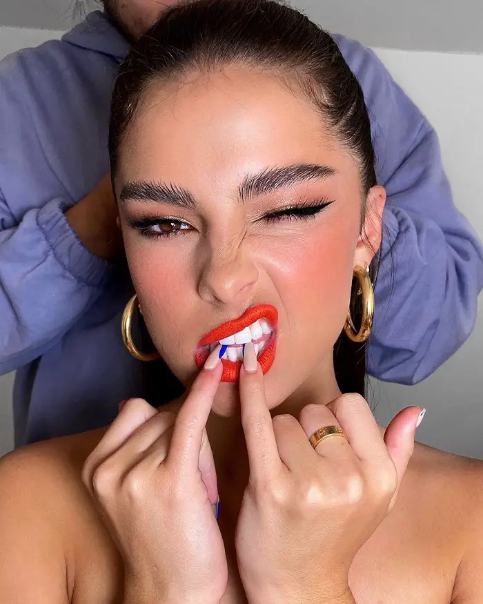 Addison Rae wearing bold lip and brows by makeup artists Patrick Ta and hair being done by Jesus Guerrero, and also with oft-worn gold hoops and that signature Cartier ring in gold.