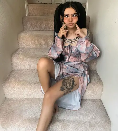 Bella Poarch pinching her cheeks sitting in the stairs.