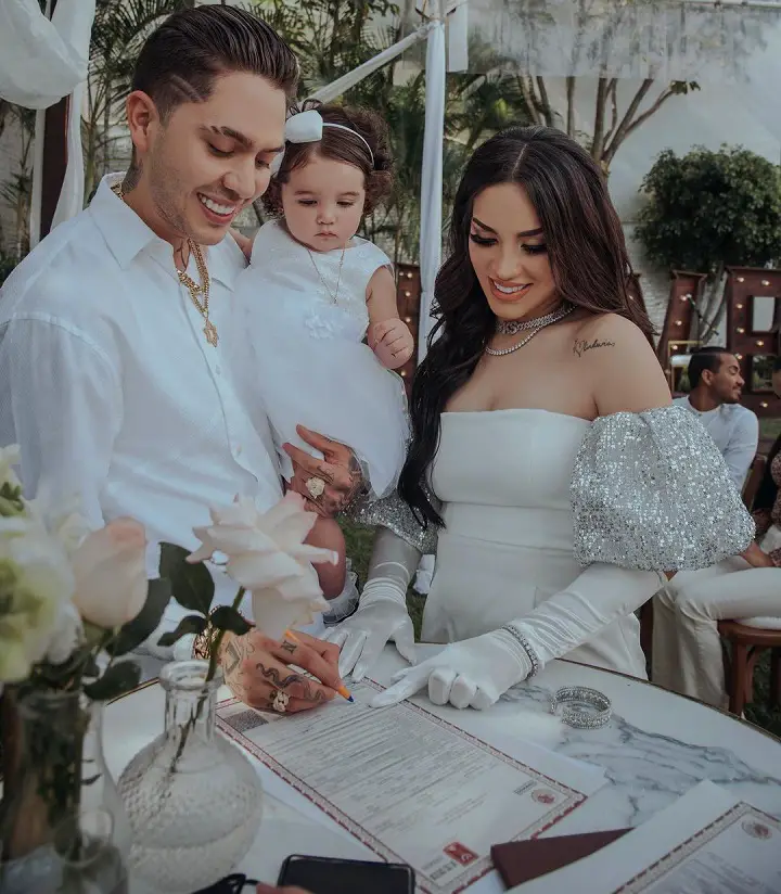 Kimberly Loaiza with her husband, JD Pantoja, signing the marriage documents while holding their daughter.