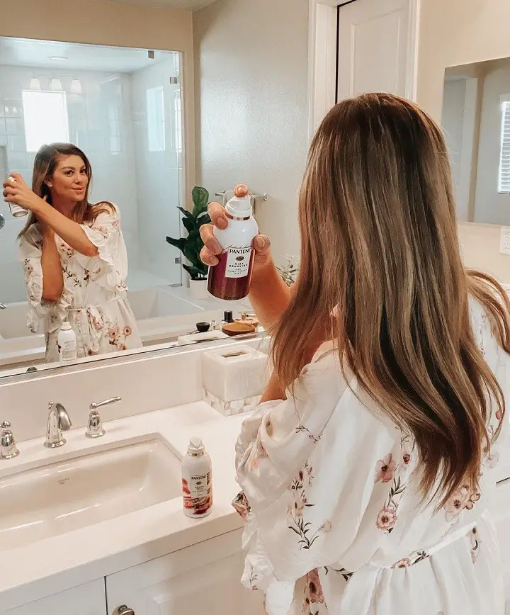 Madison Miller posing for her ad for Pantene on Instagram while looking at the mirror and subtly showing the product in her hand.