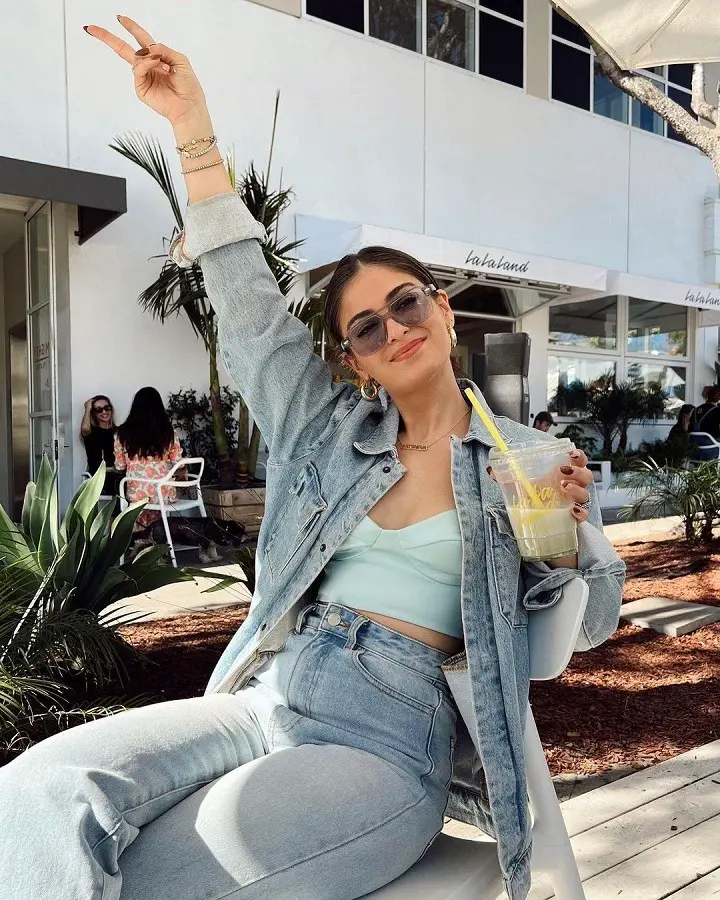 Batsheva Haart raising it up like an influencer, one hand up in the air, other with a smoothie in her hand.
