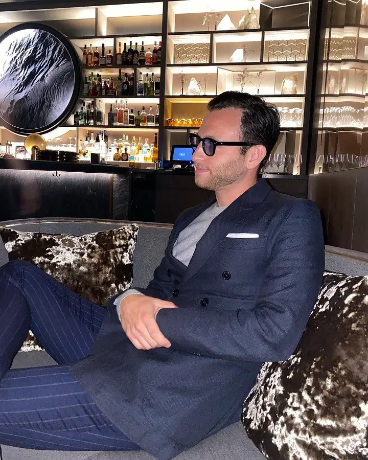 Ben Weinstein in a suit and glasses sitting relaxed on the couch.