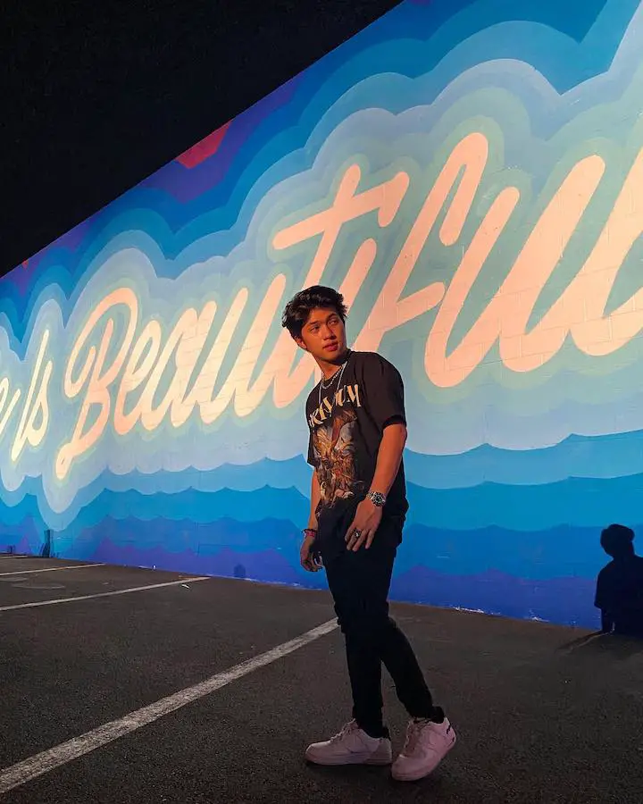 Ranz Kyle standing in front of a mural that says "Beautiful".