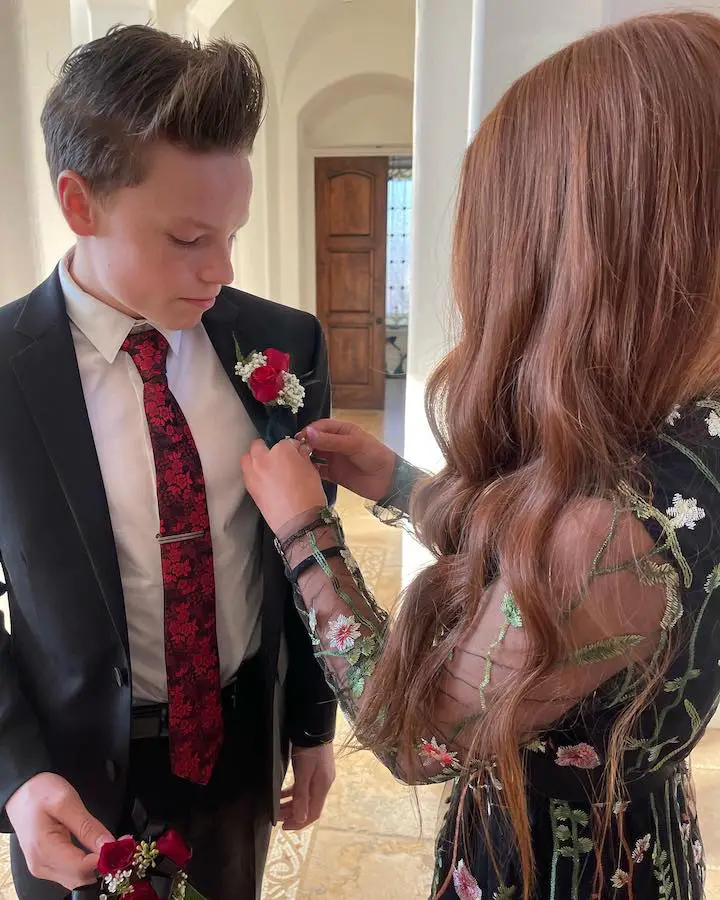 Bryton Myler (left) being put on a prom rose by a girl (right) not facing the camera.