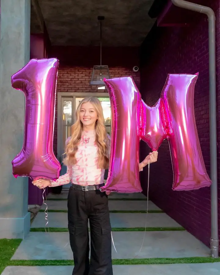 Emilt Dobson holding two inflatables that reads '1M' to mark her 1-million subscribers mark.