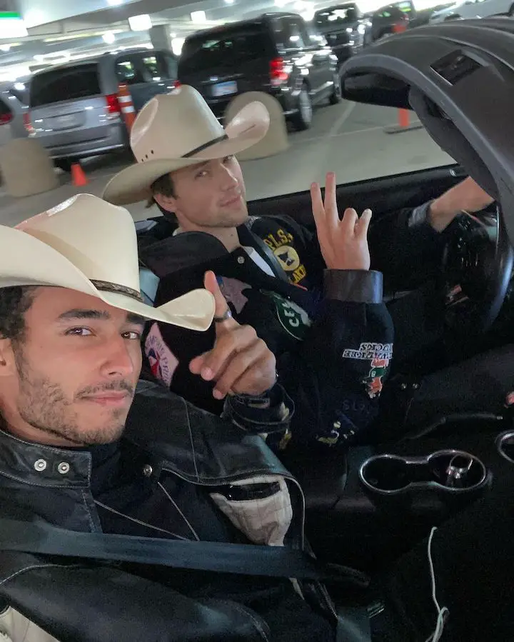 Austin Armstrong (left) with his friend (right) both with hats on while in a car as he takes a selfie.