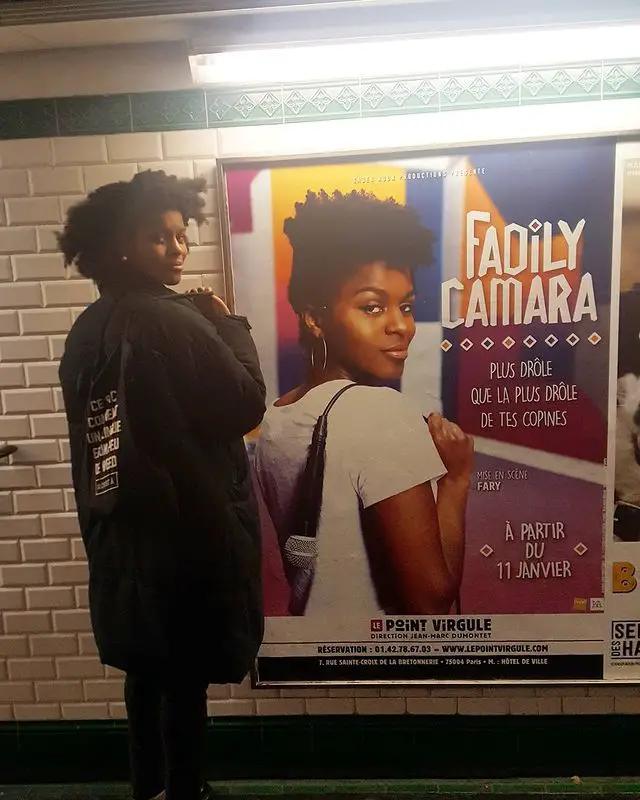 Fadily Camara replicating her own pose (a look back while facing backwards) as the one she made in an advertisement poster for her show back in 2017.