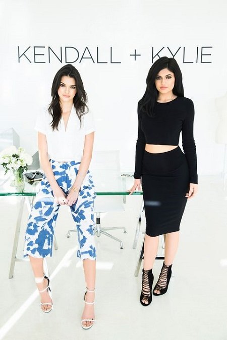 Kylie (right) and Kendall Jenner (left) posing for their line 'Kendall + Kylie' written above them.