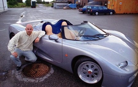von Koenigsegg sitting beside his grey CC Prototype back in 1996. He was bald but had a beard.