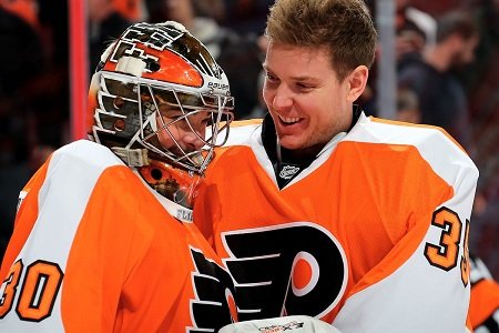 Michal Neuvirth (left) with helmet on being joked by Steve Mason (right) without a helmet.