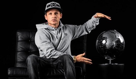 Rob Drydek showcasing a black globe while sitting on a couch with black background.