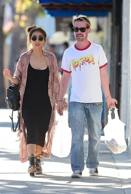 Brenda Song, net worth = $7 miillion, and Macaulay Culkin, net worth = $16 million, holding hands while walking together.