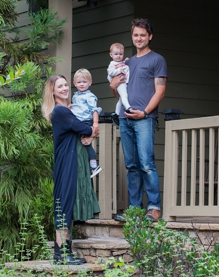 Alexandra Breckenridge and husband Casey Hooper each holding a baby in their hands at the front porch of their Atlanta home.