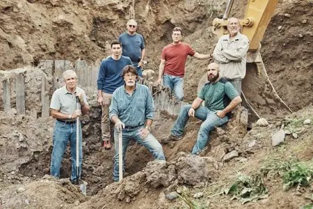 'The Curse of Oak Island' crew posing in the dirt in front of a crane.