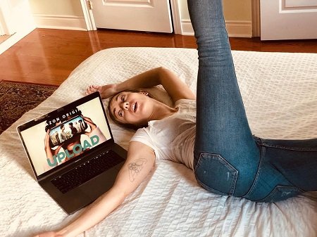 Julie Nolke in a weird pose on her bed with a laptop screen shown.