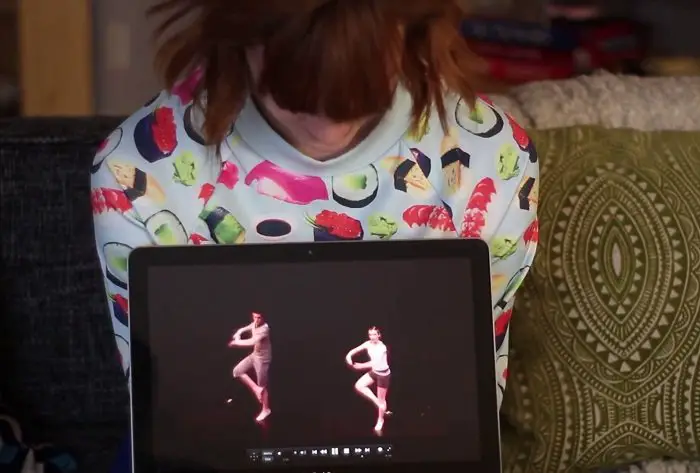 Julie Nolke looking at a clip of her dancing as a young girl on her laptop below, on her lap.