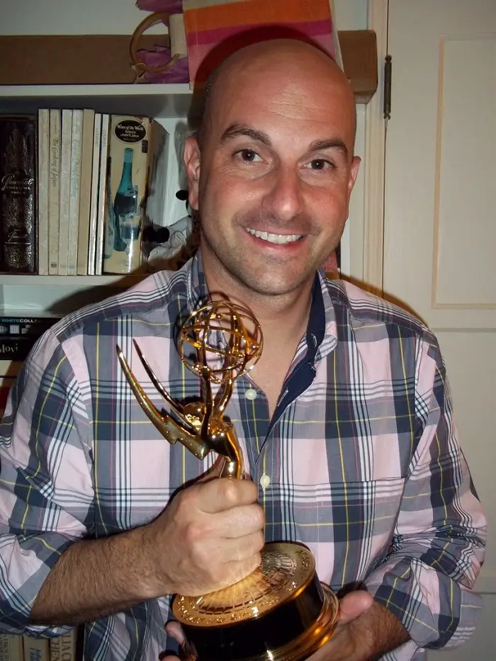 Edward Lawrence holding his Emmy award and smiling at the camera.
