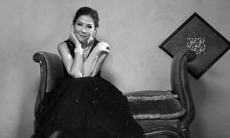 Anna Shay sitting on an old-style couch posing for a photo.