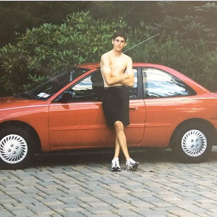Ben Aaron shirtless in his backyard leaning on to his red car in 1997.