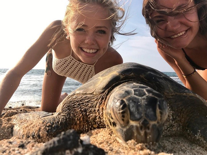 Annalisa Cochrane (left) with her friend (right) and a turtle in front of her as a selfie.