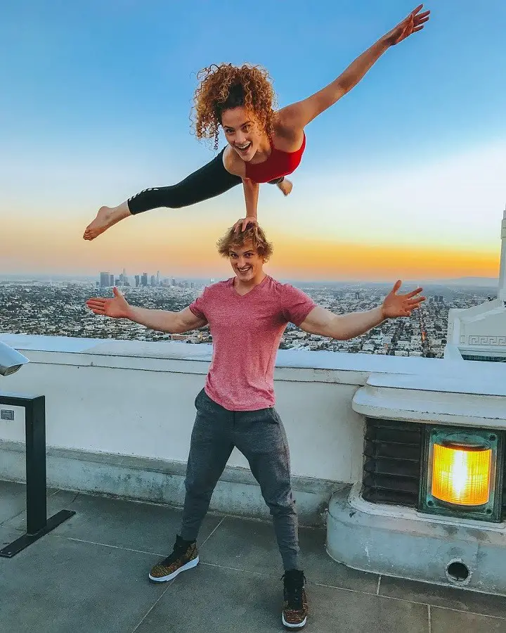 Sofie Dossi standing on Jake Paul's head on one hand.
