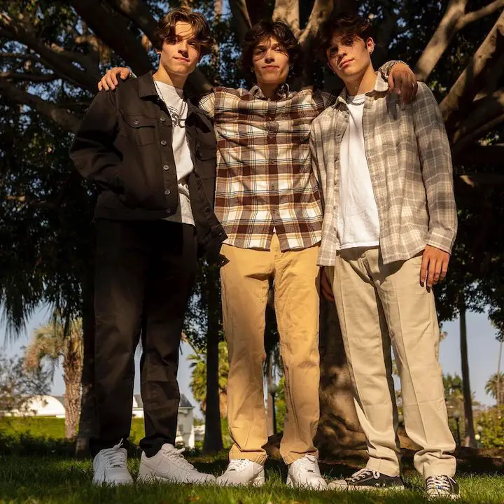 Matthew Sturniolo (left) with his two triplets brothers in front of a big tree.