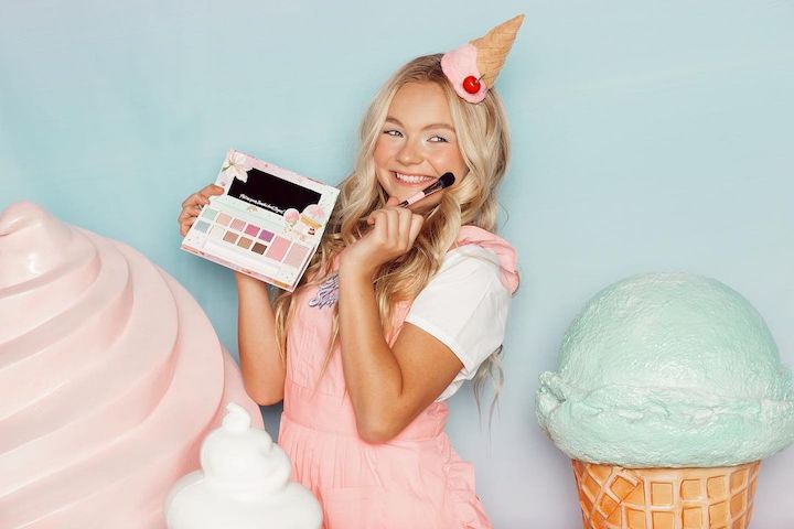 Pressley Hosbach holding the 'Oh, So Sweet Eye & Cheek Palette' from 'Petite 'n Pretty' in an ice-cream themed background.