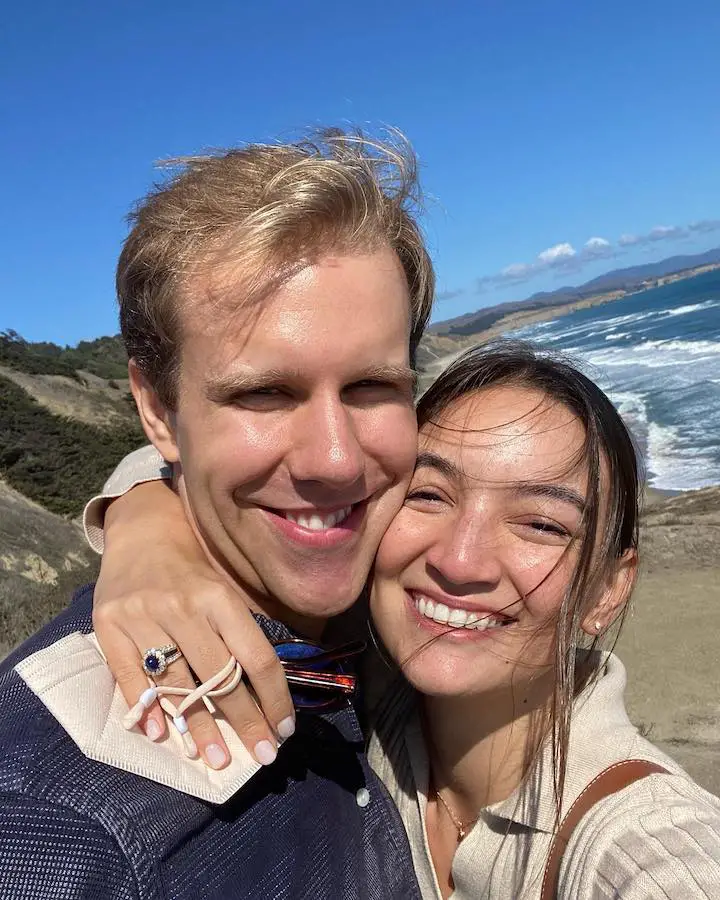 Emily Mariko (right) with her longtime boyfriend turned fiance Matt Rickard (left) while showcasing her ring around his neck.