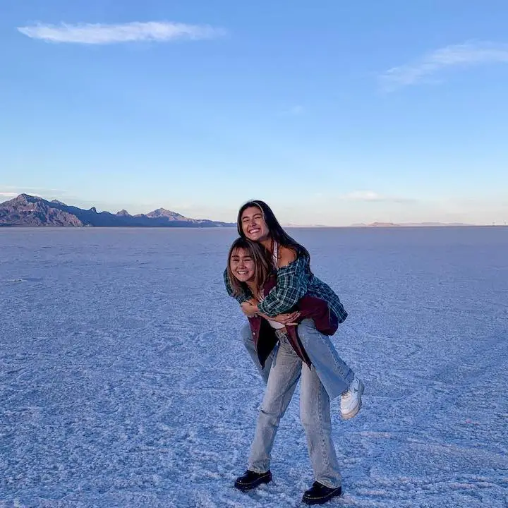 Erika Titus carrying her sister Kirsten Titus on her back in a dry desert morning background.