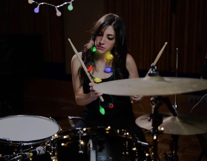 Lena Zawaideh in the middle of a drumming session with a light Christmas theme.