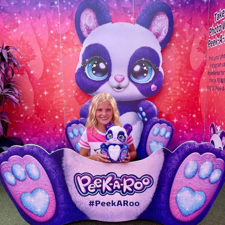 Payton Delu Myler holding a Peek-A-Roo doll at the LA Zoo's Peek-A-Roo Exhibit while inside a giant plushie Peek-A-Roo pouch.