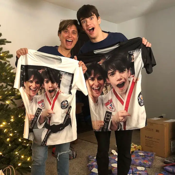 Ethan Fineshriber (right) and his mother Mara Rudolph Fineshriber (left) both holding a T-shirt with a photo of the two after his championship win printed on them.