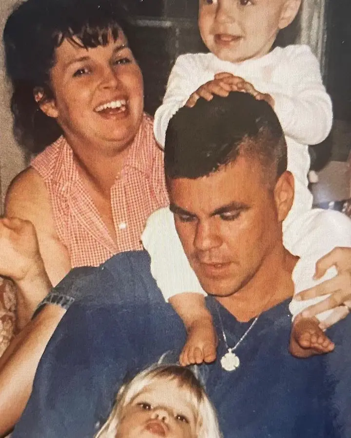 Kristin Marino's firefighter father carrying her brother Tyler Marino on his shoulders with Kristin stretching herself to be in frame and her mother behind them.