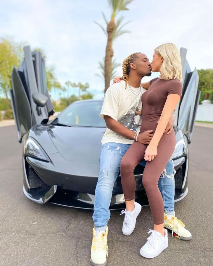Charles Davis (left) and Alyssa Hyde (right) kissing while sitting on the hood of his dream McLaren car.