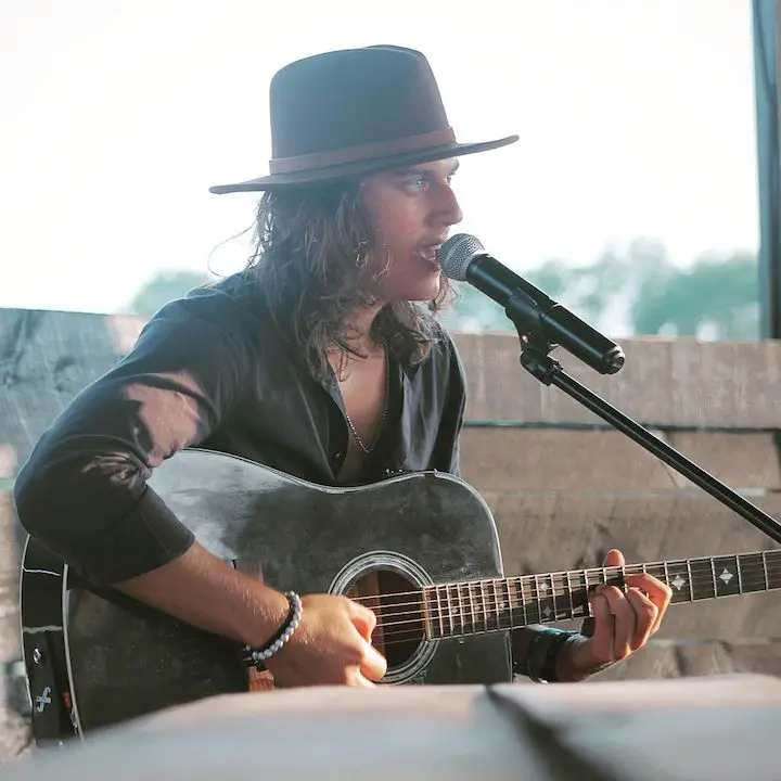 Matt Cooper in the midst of singing with his guitar.