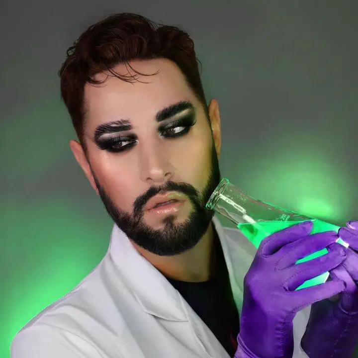 Robert Welsh in a Halloween Dexters lab-themed makeup while holding a green-colored liquid in a flask.