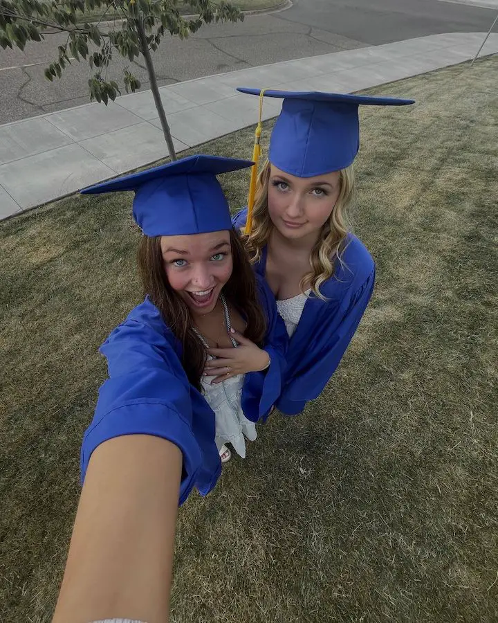 Signa Mae (left) with her friend Kalissa Marcella (right) taking an overhead selfie in their graduation gowns.