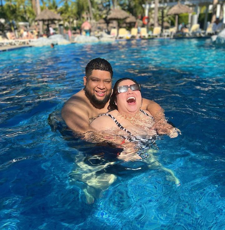 Stephanie Valentine, aka Glamzilla, being embraced by her boyfriend Byron from behind as she laughs in a pool.