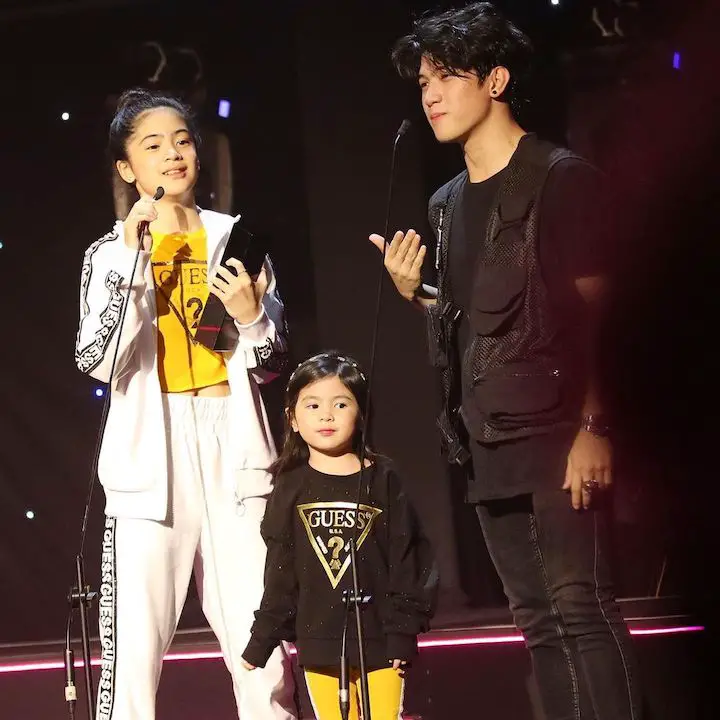 Natalia Guerrero (center) on a stage with Niana Guerrero (left) and Ranz Kyle (right) in speaking mode.