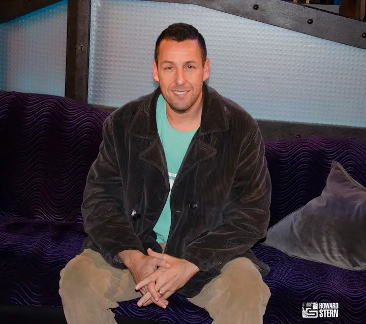Adam Sandler posing on the infamous couch on the Howard Stern show during his 2015 appearance.