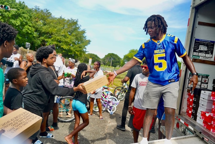 Teddy Bridgewater handing out packages during a food-distribution-to-the-homeless session in his #5 jersey.
